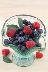 Blueberries and raspberries in vintage glass basket