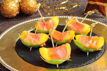 Skewered peaches with prosciutto and basil on a Christmas table