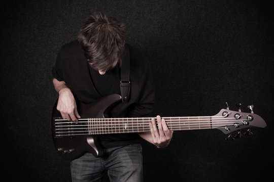 Man Playing On Bass Guitar In Studio