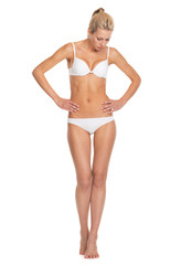 Full length portrait of young woman in lingerie looking on belly