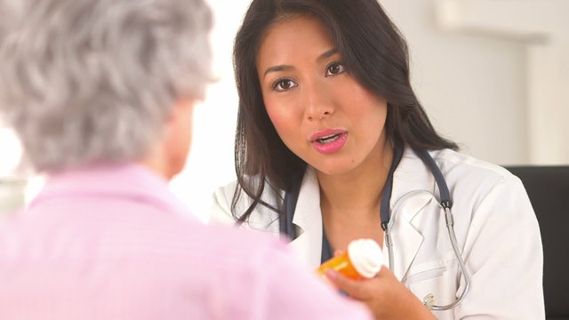 Asian doctor prescribing medication to mature woman patient