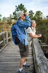 Senior Couple Hiking and Birdwatching on Old Wooden Foot Bridge - 57900670