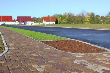 Neues Betonpflaster auf Parkstreifen und Gehweg mit Bauminsel