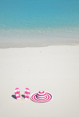 Fototapeta na wymiar Flip-flops and hat on the beach