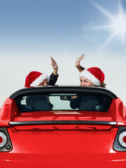 Two Santa Claus waving of the hand in a roadster