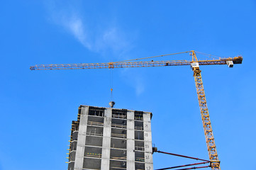 Crane and building construction site against blue sky