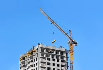 Crane and building construction site against blue sky