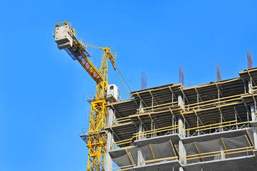 Fototapeta premium Crane and building construction site against blue sky