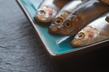 Fresh tasty raw sprats on serving dish