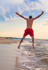 Fototapeta na wymiar Happy man jumping on the beach