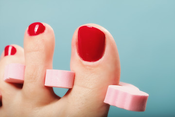 foot pedicure applying red toenails on blue