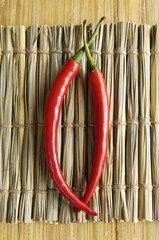 Two chili pepper isolated on Texture of straw.