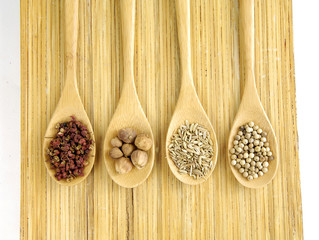 Assortment of spices in a wooden spoons on wooden board