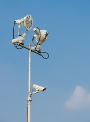 Floodlight with surveillance cameras in blue sky
