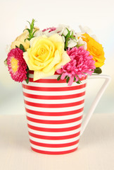 Beautiful bouquet of bright flowers in color mug,