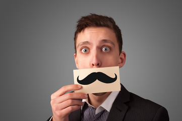 Happy businessman holding funny mustache card on his mouth