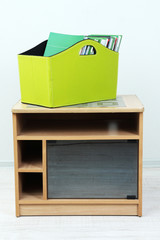 Magazines and folders in green box on bedside table in room