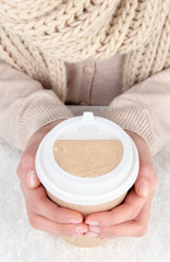 Hot drink in paper cup in hands with snow close up