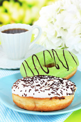 Sweet donuts with cup of tea on table on bright background