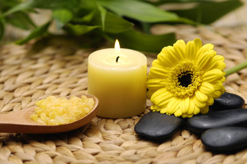 Obraz na płótnie Canvas candle and daisies flower and bamboo leaf on wicker mat