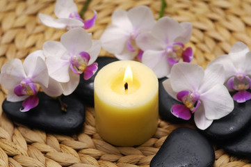 Yellow Candle and stones with orchid with stones on mat