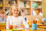 Little schoolgirl sitting behind school desk 