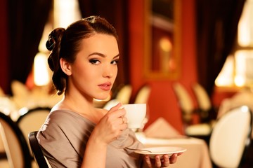 Beautiful young girl with cup of coffee  in a restaurant