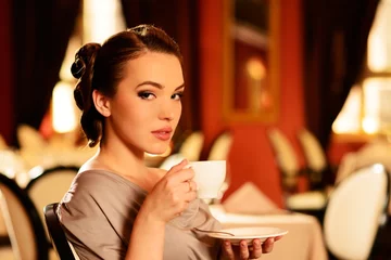 Cercles muraux Restaurant Beautiful young girl with cup of coffee  in a restaurant