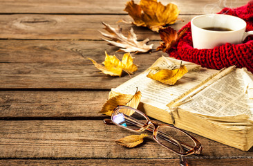 Hot coffee, book, glasses and autumn leaves on wood