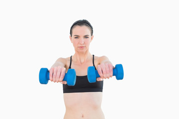 Fototapeta na wymiar Portrait of a serious young woman with dumbbells