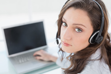 Serious businesswoman wearing headset in front of laptop