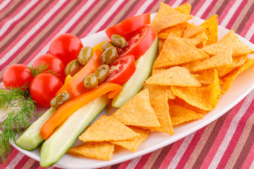 Vegetables, olives, nachos in plate