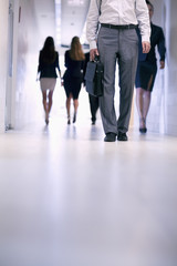 Fototapeta na wymiar Low view of people walking down the corridor in an office building