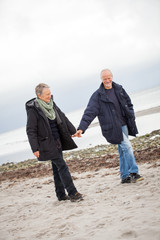 älteres glückliches paar macht einen strand spaziergang