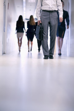 Low View Of People Walking Down The Corridor In An Office Building