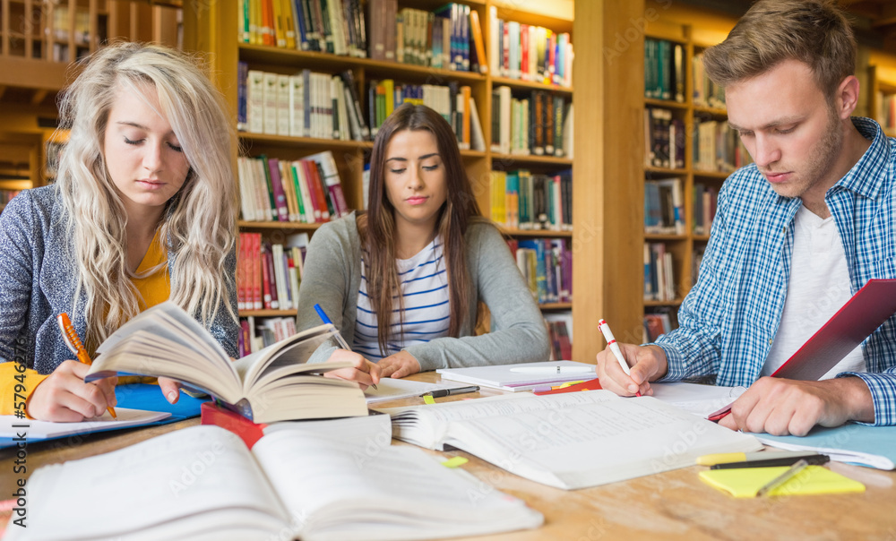 Poster students writing notes at library desk