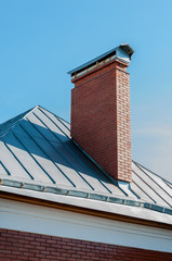 brick chimney on the roof covered by metal