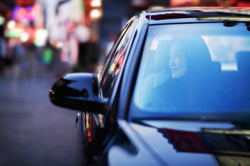 Serene woman looking through car window at the city nightlife