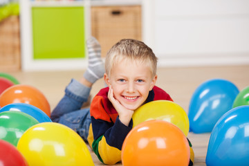 süßer kleiner junge liegt zwischen luftballons