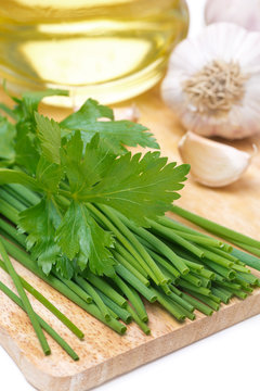 chives, parsley, garlic and olive oil on a wooden board
