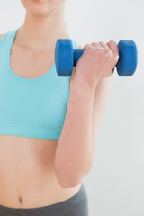 Fototapeta na wymiar Close up mid section of woman exercising with dumbbell