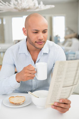 Fototapeta na wymiar Man drinking coffee while reading newspaper at home
