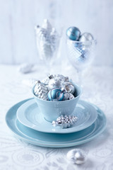 Silver and blue christmas ornaments in a tea cup