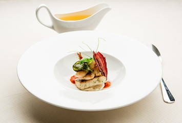 Bowl with fish fillet and dish with hot broth