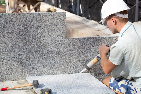 Construction worker sealing joints between ceramic Tiles