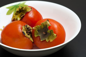 persimmons in bowl on wooden table