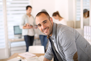 Smiling young man in office working on laptop
