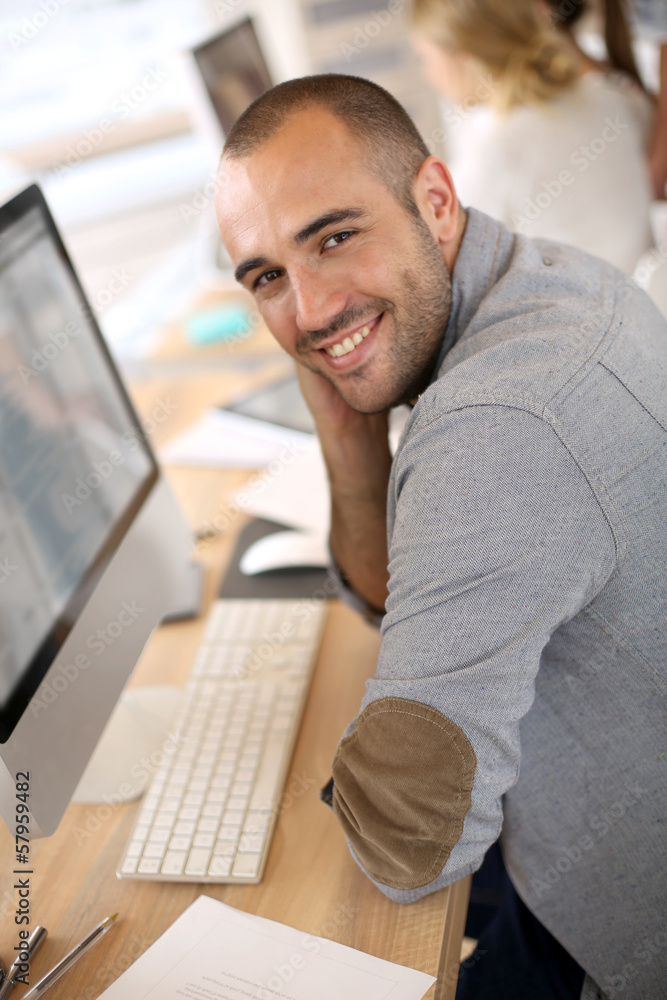 Aufkleber cheerful guy sitting in front of desktop computer