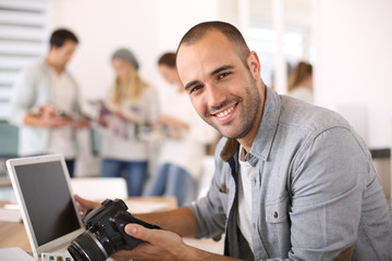 CHeerful reporter working in office on laptop