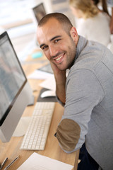 Cheerful guy sitting in front of desktop computer
